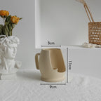 Beige ceramic mug with dimensions labeled on a white surface.