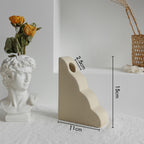 White stone sculpture with floral arrangement next to a beige stone sculpture with measurements on a light gray background