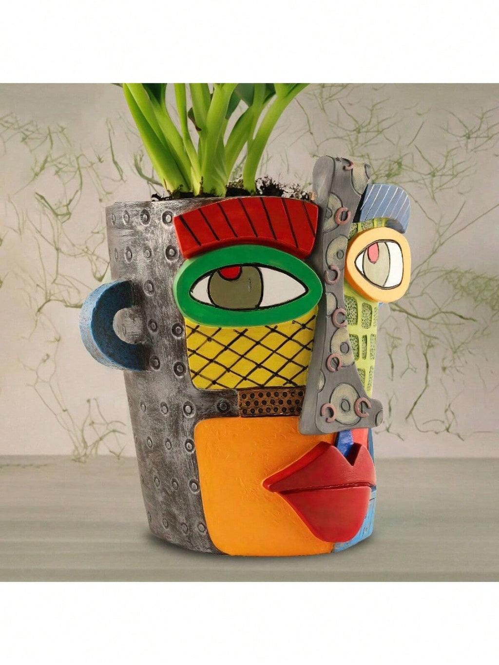 Colorful ceramic vase with face design containing a plant on a neutral background