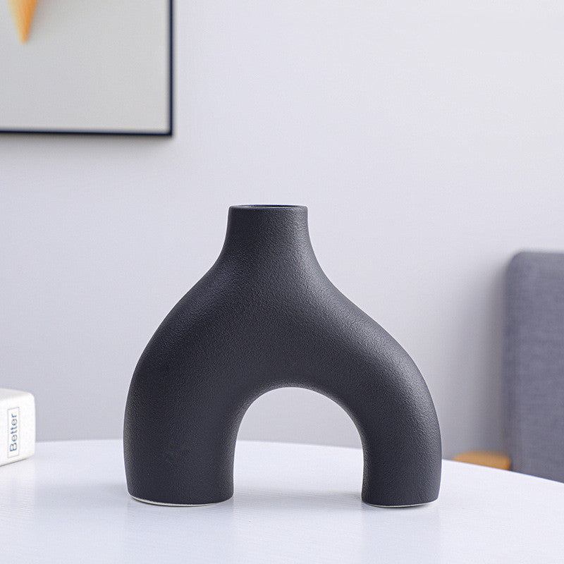 Black vase on a white surface with a neutral background