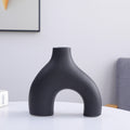 Black vase on a white surface with a neutral background