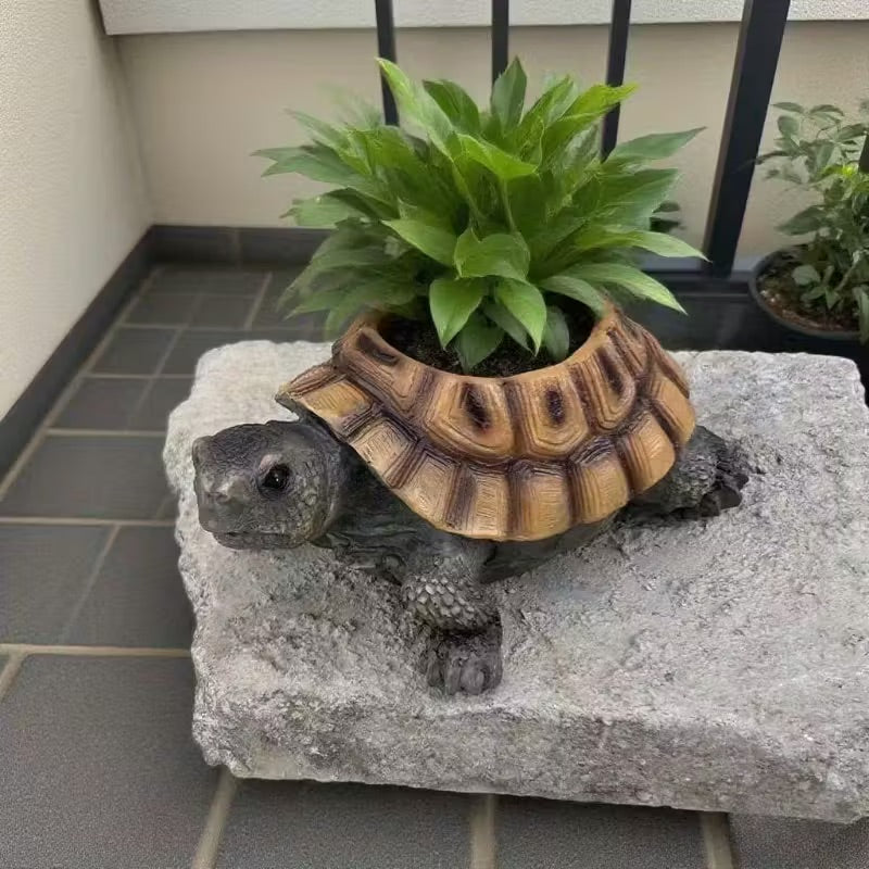Decorative turtle with a plant on its back on a stone surface.