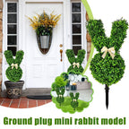 Decorative greenery shaped like a rabbit with a bow, placed in front of a white door.