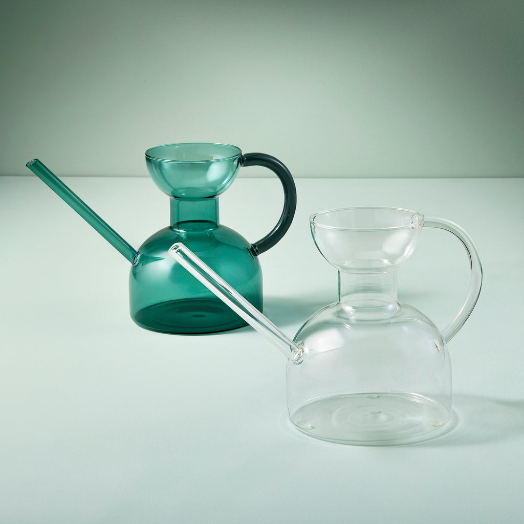 Two glass pitchers, one green and one clear, on a light gray background