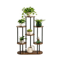 A 6-tier corner plant stand with dark brown wooden shelves and black metal legs, shown holding several potted green plants and decorative vessels on a light white background. 