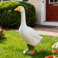 Decorative goose statue on grass in front of a house with a red door.