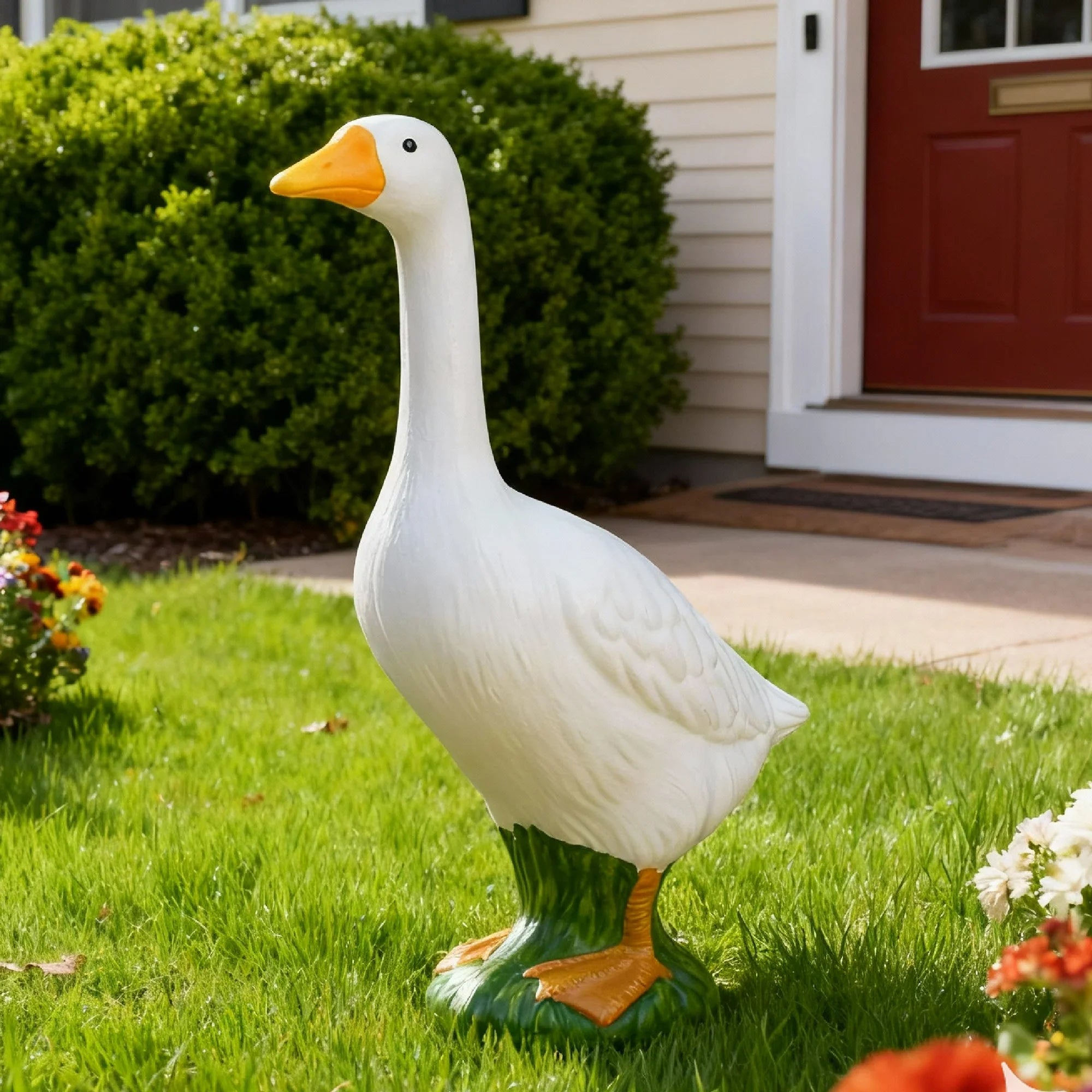 Decorative goose statue on grass in front of a house with a red door.
