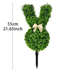 Decorative bunny topiary made of green foliage with a bow on a white background