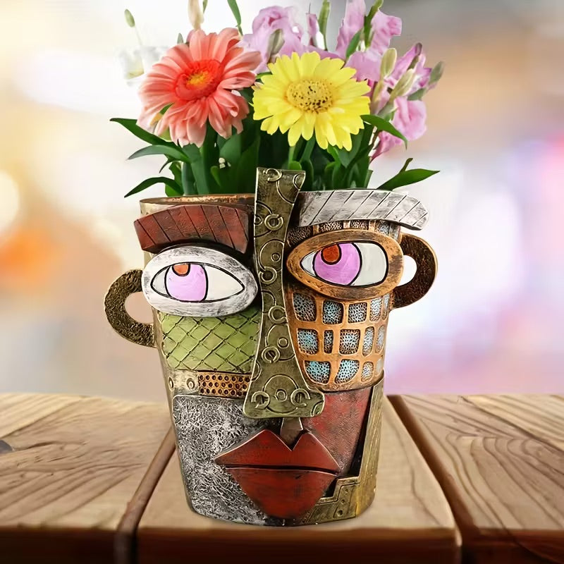 Decorative vase with face design holding flowers on a wooden surface