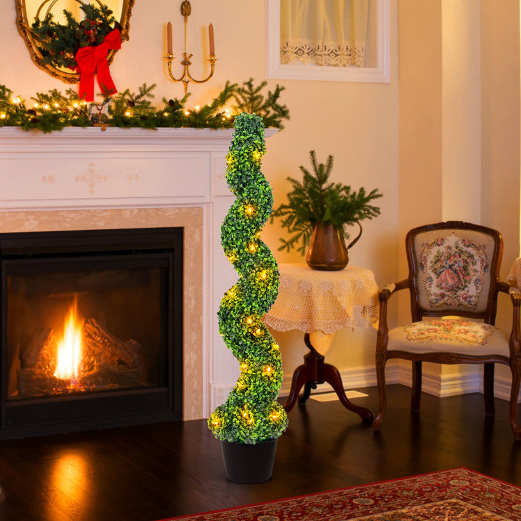 Decorative spiral plant with lights in a cozy living room with fireplace and Christmas decorations.